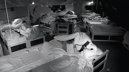 Marcus Akin talks to Noirin Kelly under the covers on her bed in the dark